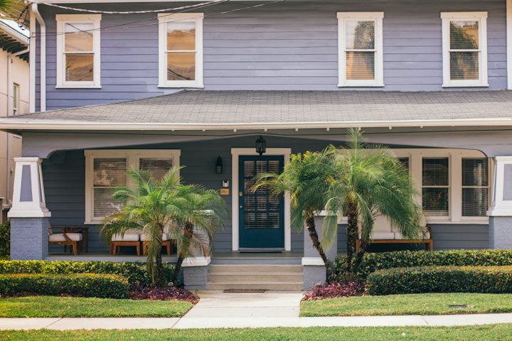 Blue two-story house with a front porch and palm trees