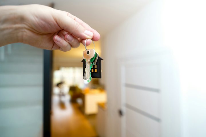 Hand holding a set of house keys inside a front doorway