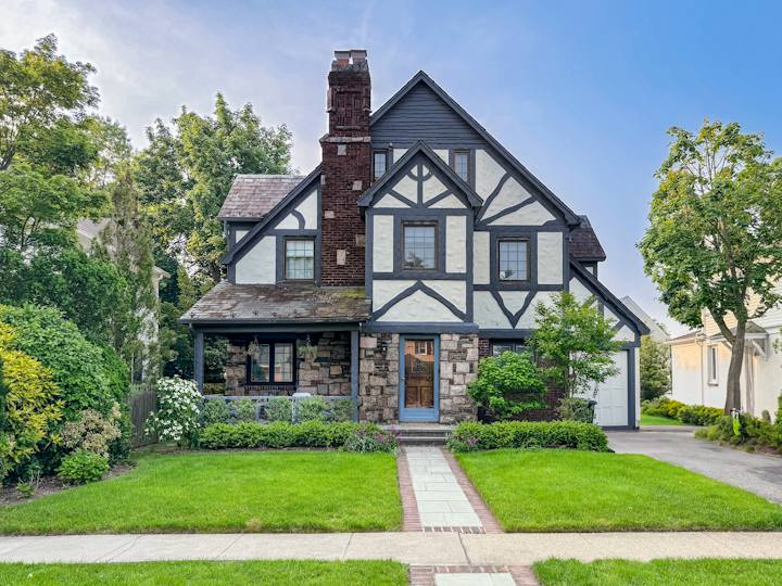 Tudor-style house with a stone chimney and a front walkway